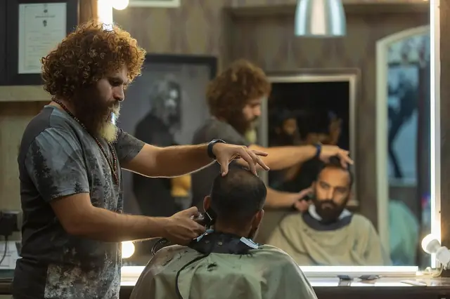 Barber cutting a customer's hair in a busy barbershop with mirrors