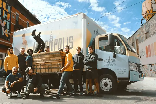 Moving crew posing in front of a box truck on a city street