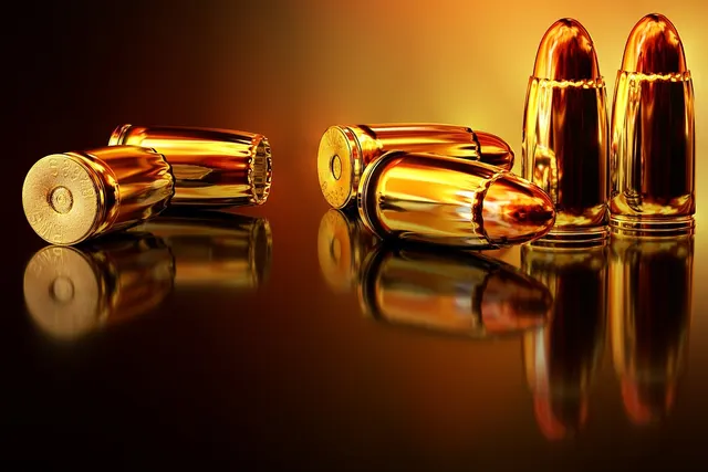 Brass pistol cartridges, some standing upright and some lying on their sides, on a glossy reflective surface in warm light