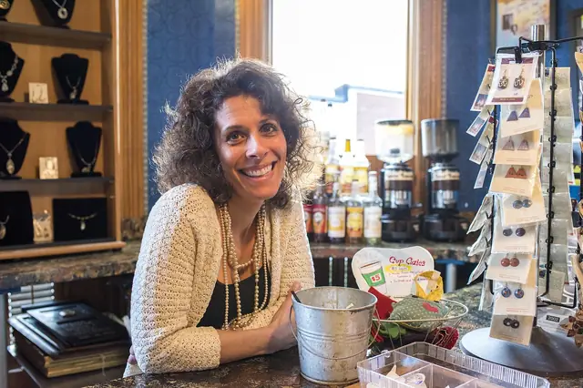 Smiling shop owner leaning on a counter in a jewelry and gift store
