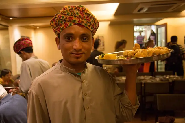 Smiling server holding a tray of fried snacks