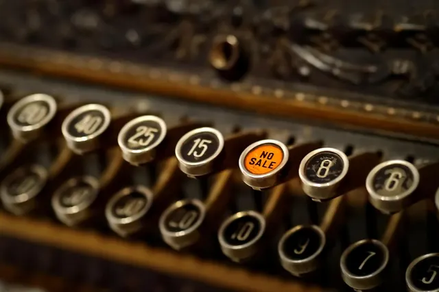 Close-up of vintage cash register keys with numbered buttons and an orange NO SALE key in the center