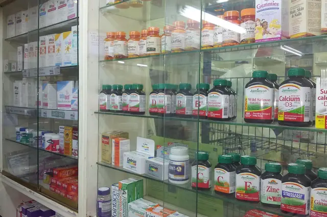 Glass shelves stocked with vitamin and supplement bottles in a pharmacy