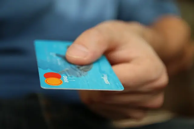 Hand holding out a blue credit card