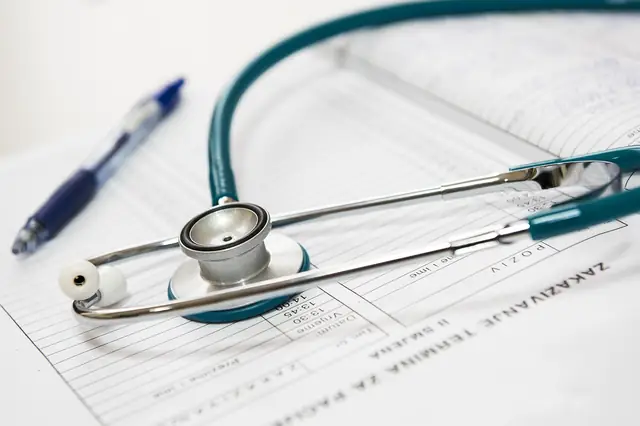 Stethoscope and blue pen lying on a printed medical form
