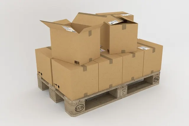 Stacked cardboard shipping boxes, some open, with barcode labels on a wooden pallet against a plain white background