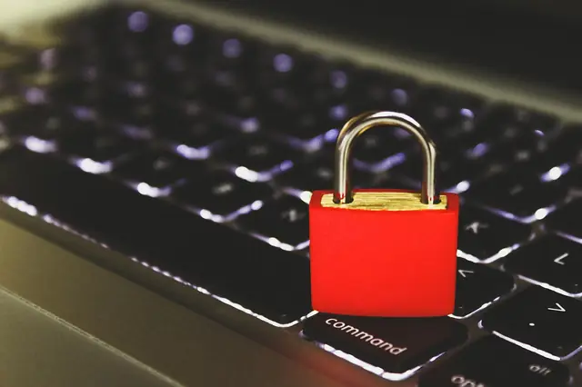 Red padlock resting on a backlit laptop keyboard