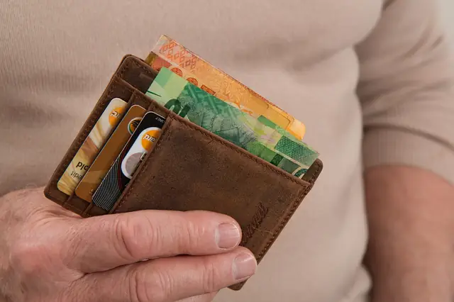 Hand holding a leather wallet stuffed with cards and cash