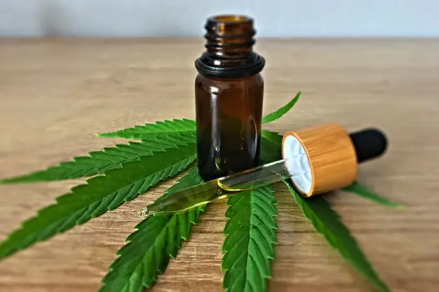 Amber dropper bottle of oil resting on a cannabis leaf