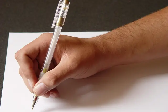 Close-up of a hand writing with a pen on blank paper