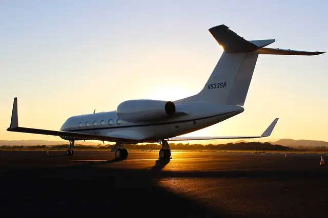 Private jet parked on a runway at sunset