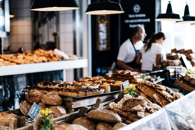 Bakers behind a counter piled with breads and pastries