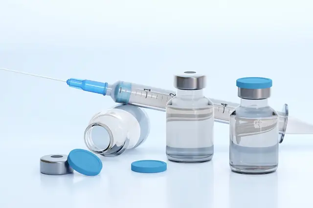 Glass medicine vials and a syringe on a white surface