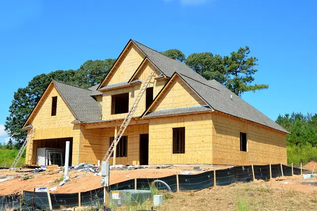 Wood-framed house under construction with sheathing and a ladder