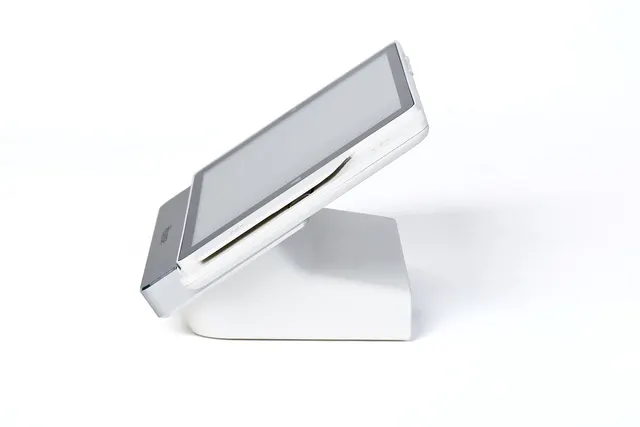 Side view of a white tablet POS stand with a built-in card reader slot, angled on a white background