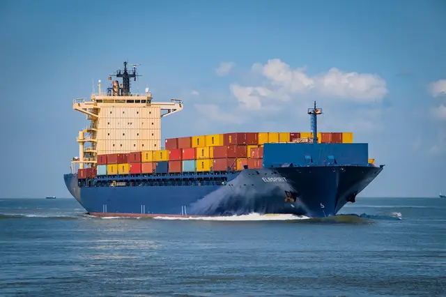 Loaded container ship sailing on open water under blue sky