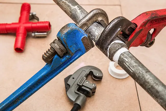 Pipe wrenches and a pipe cutter gripping crossed metal pipes