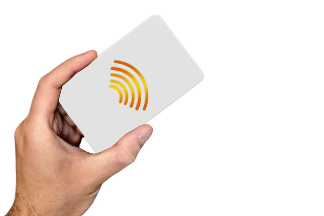Hand holding a blank white card with an orange contactless payment symbol against a black background