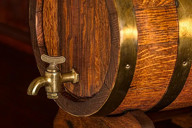 Close-up of an oak barrel with brass bands and a brass spigot tap, resting on a wooden stand in warm light