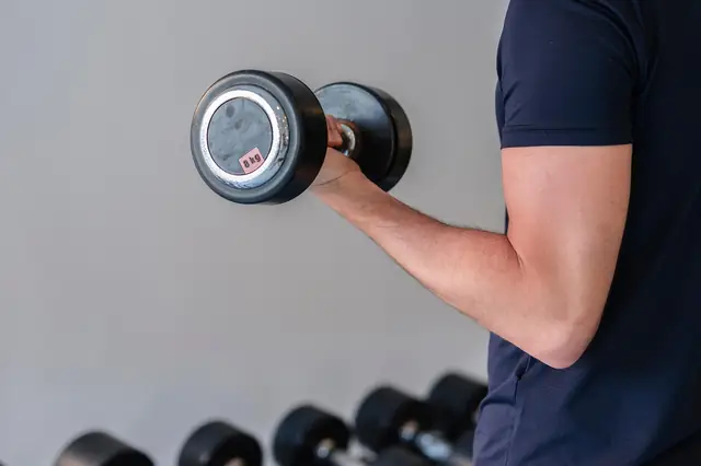 Man lifting a dumbbell in front of a weight rack