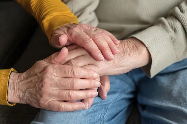 Caregiver holding an elderly person's hands