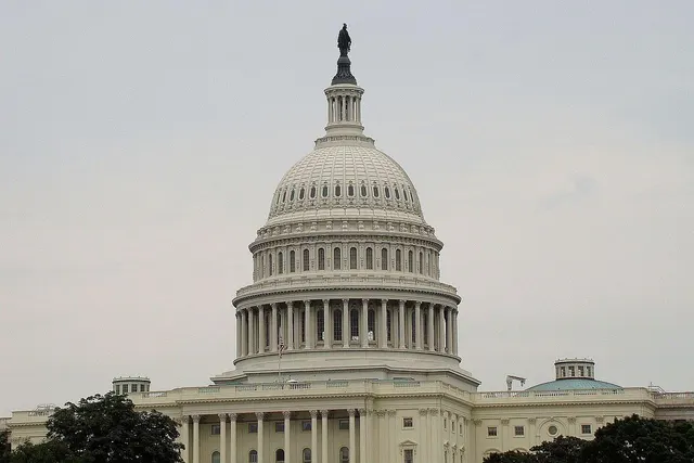 U.S. Capitol dome in Washington, D.C. under an overcast sky, with trees in front of the building
