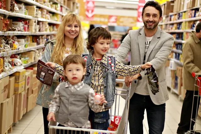 Family pushing a shopping cart down a grocery aisle