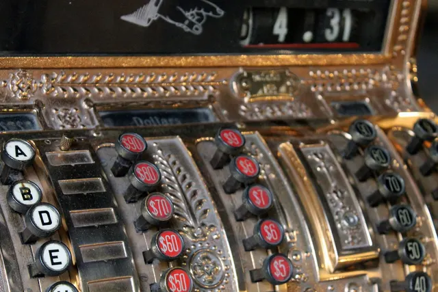 Close-up of an ornate antique brass cash register with red and black dollar and cents keys and a 4.31 sale display