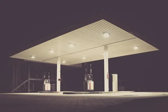Empty gas station at night with two fuel pumps under a brightly lit white canopy on a dark forecourt