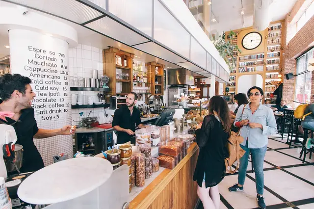 Busy coffee shop counter with a chalk menu board and customers