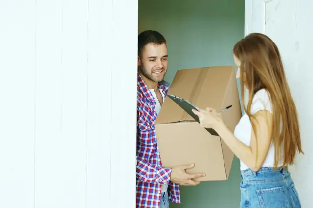 Couple signing for a package delivery at their front door