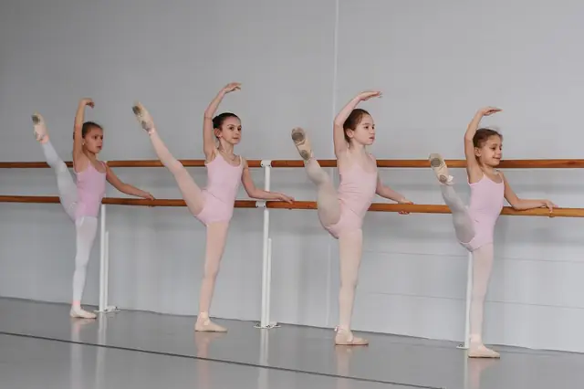 Young ballet students stretching at a barre in a studio