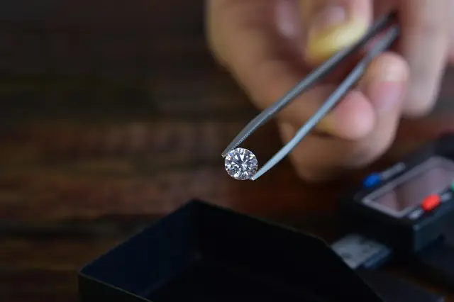 Tweezers holding a loose diamond over a jeweler's case