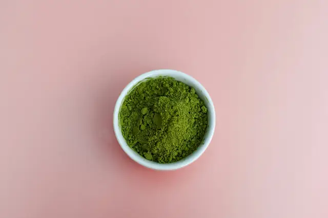 Bowl of fine green herbal powder on a pink surface