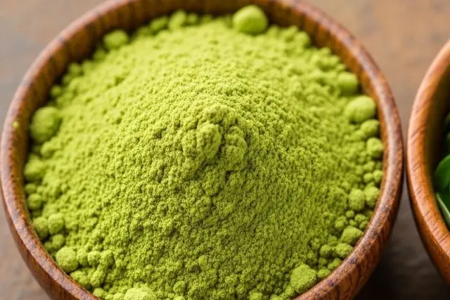 Close-up of fine green powder heaped in a wooden bowl