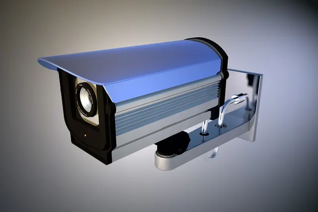 3D render of a silver and blue wall-mounted security camera with a sun hood against a gray gradient background