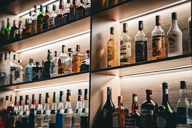 Lit shelves stocked with rows of liquor and spirit bottles