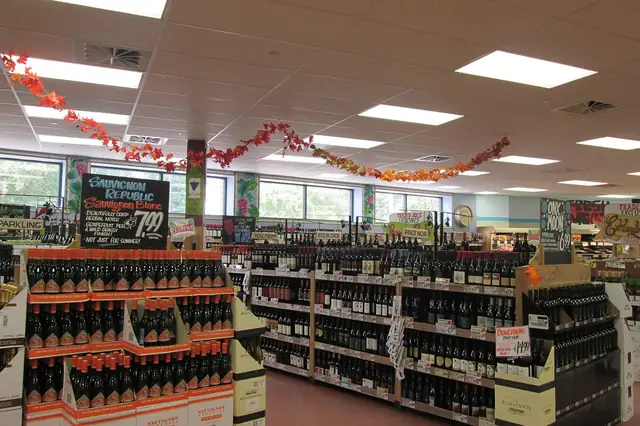 Store aisles lined with wine displays under festive hanging garlands