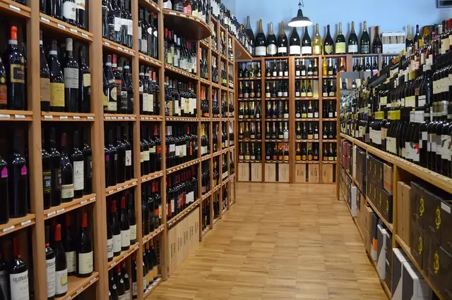 Long aisle of a wine shop with tall wooden bottle shelves