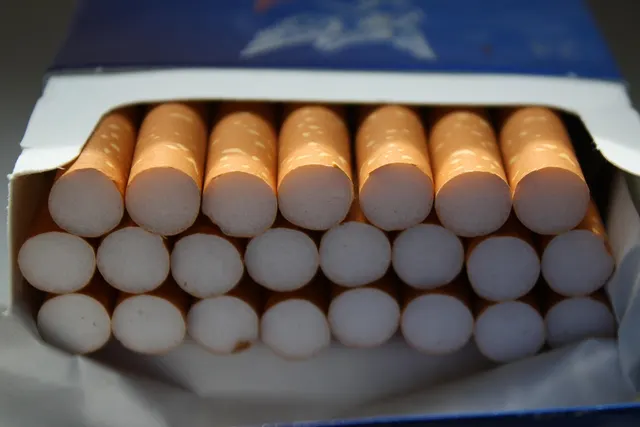 Close-up of an open cigarette pack showing three rows of orange-tipped filters inside foil lining