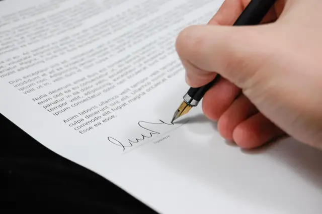 Hand signing a printed contract with a fountain pen
