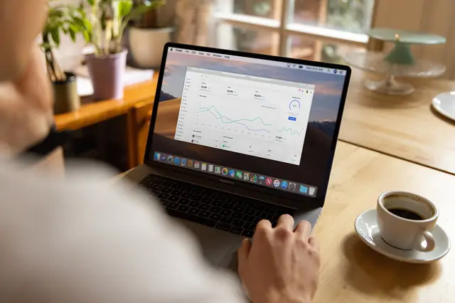 Person viewing a sales dashboard on a laptop next to coffee