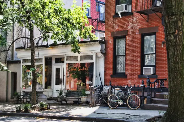 Brick townhouses and a small storefront on a leafy city street