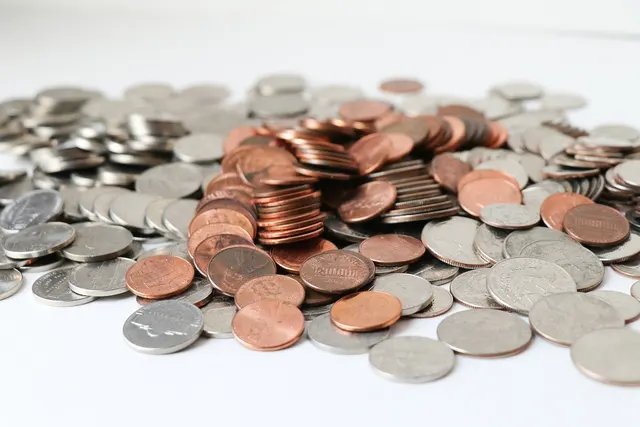 Pile of US pennies, nickels, dimes and quarters scattered on a white surface