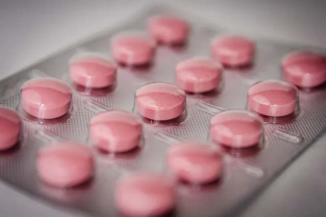 Close-up of pink round tablets sealed in a silver blister pack, with shallow depth of field