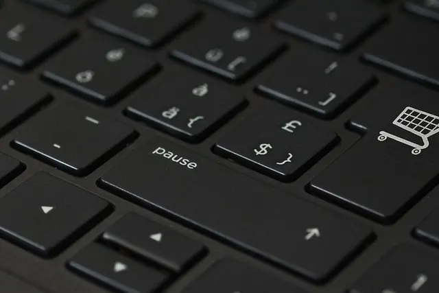 Close-up of a black laptop keyboard with a shopping cart icon on the enter key beside pound and dollar symbol keys