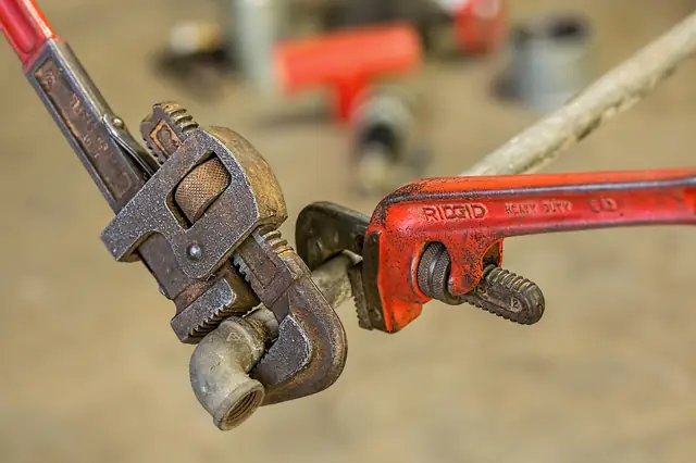 Two rusty pipe wrenches gripping each other