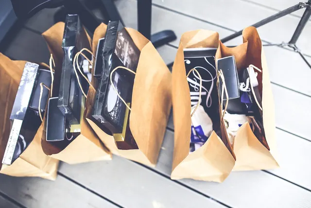 Four brown paper shopping bags filled with boxed purchases sitting on a gray wooden deck