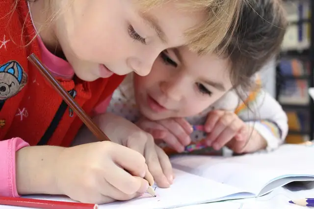 Young girl writing in a notebook at a school desk