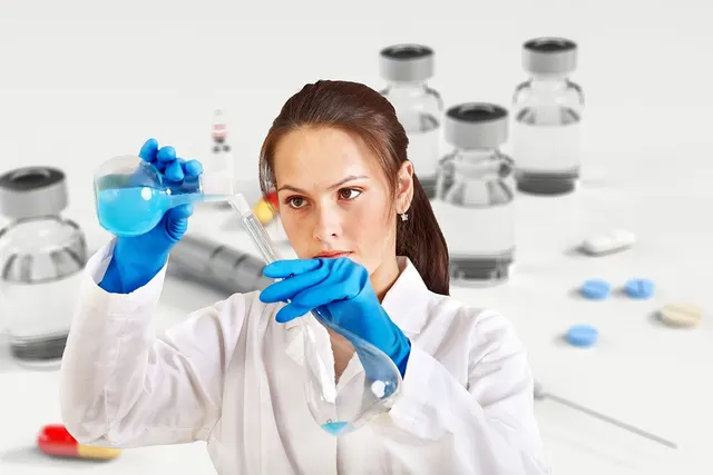 Scientist in a white lab coat and blue gloves examining blue liquid in glass flasks, with vials and pills behind her